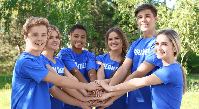 Young people putting hands together outdoors