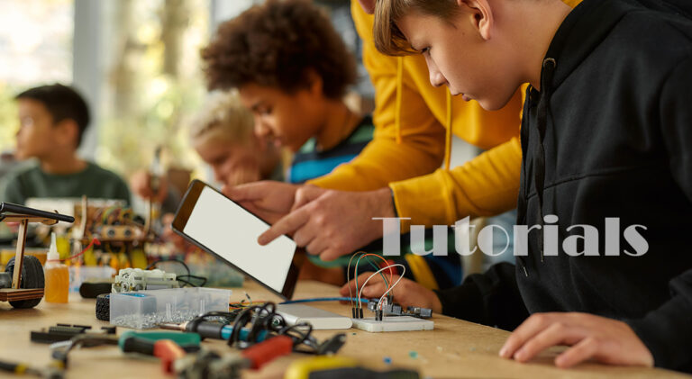 Sharing ideas. Cropped shot of young technicians working with a wiring kit at a stem robotics class. Male teacher is helping them, giving advice, using tablet pc