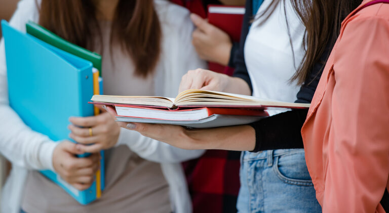 Group of four attractive asian college students standing togethe