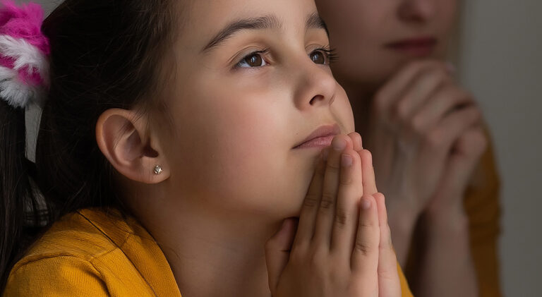 Mother and daughter reading from the bible and praying
