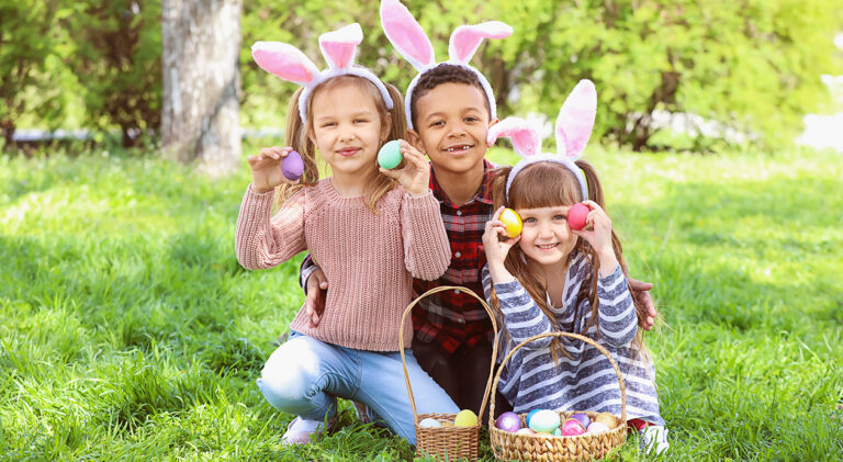 Little children with Easter eggs and bunny ears in park