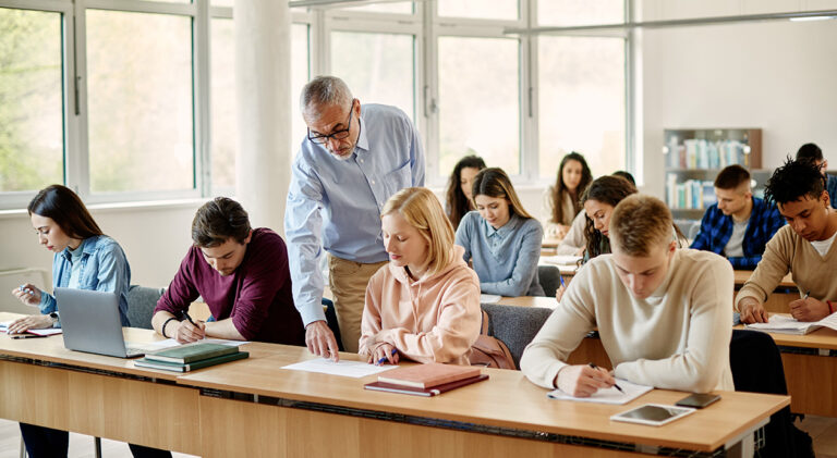 Mature professor assisting his student on a class at university classroom